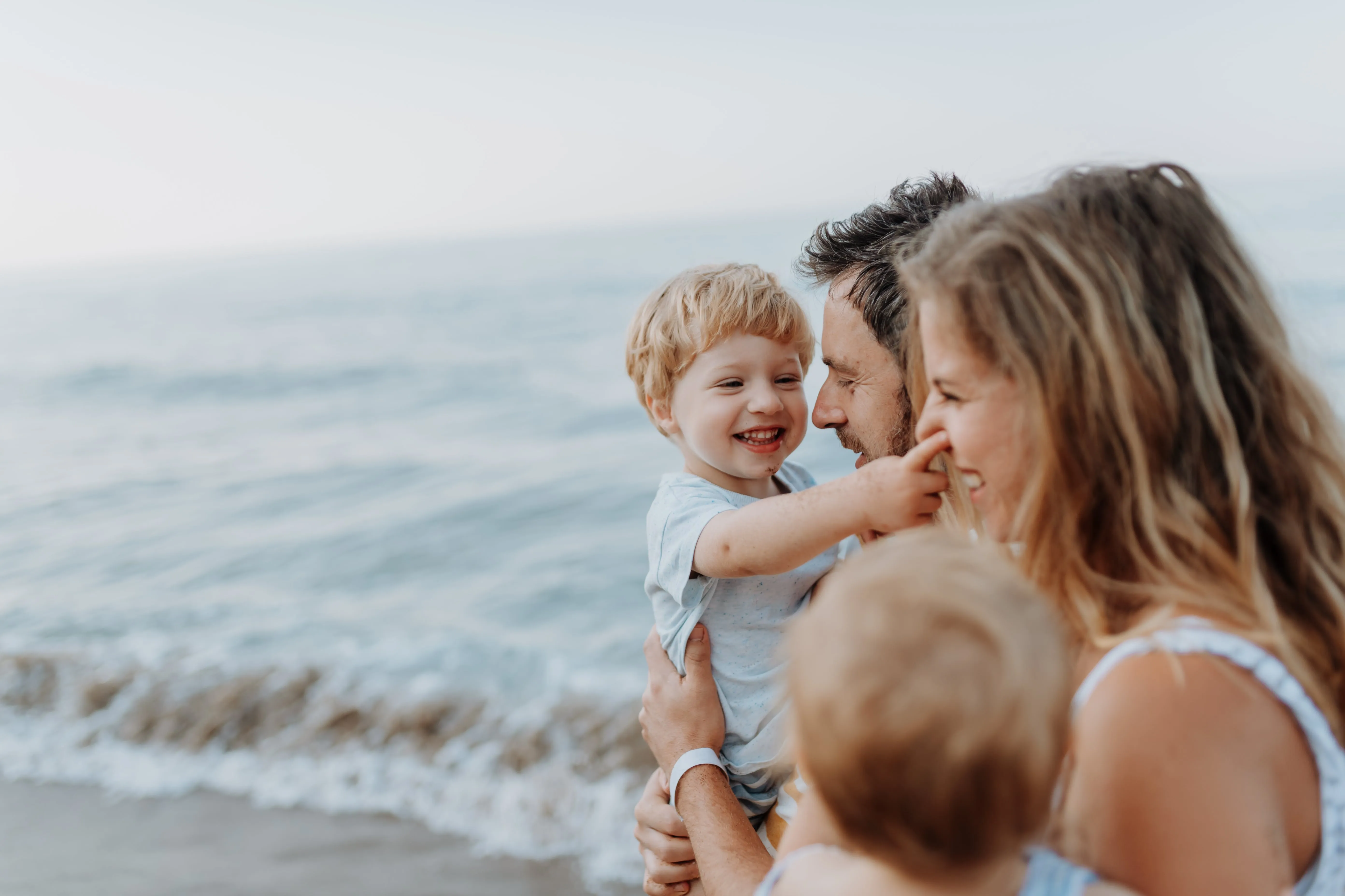 Parents with small children enjoying summer evening by the sea